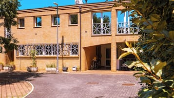A building with a brick facade, large windows, and a paved courtyard.
