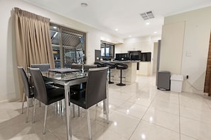 A modern kitchen with white cabinets, a black countertop, and a stainless steel range hood.