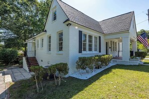 A two-story house with a front porch, a small garden, and an American flag. - White Modern Retreat | Near Fort Moore & Downtown (Columbus)