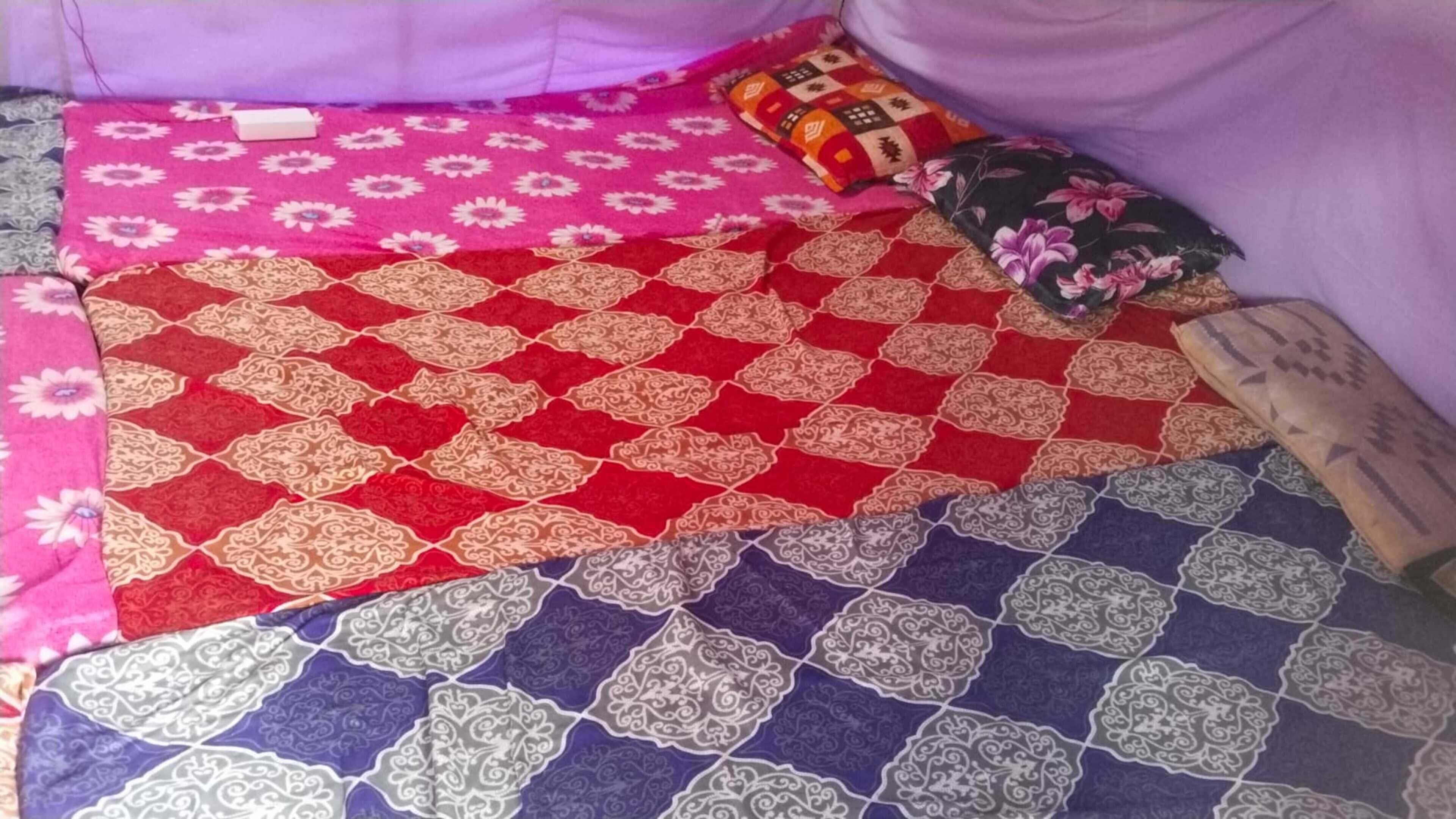A bed with multiple patterned bedspreads.