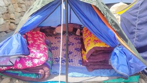 Una carpa con zona de descanso, una cama y espacio para guardar objetos.