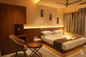 A modern hotel room with a bed, a chair, a small table, and a ceiling fan.