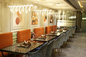 A long dining table with chairs, a chandelier, and artwork on the walls.