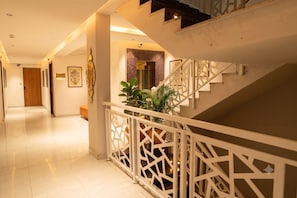 Interior moderno de hotel con escalera, pasillo y área de recepción.