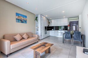 A modern living room with a sofa, coffee table, and dining area with chairs. - Modern 2 bedroom apartment, 2 balconies BZAR1-1 (St. Paul’s Bay)