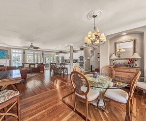 A spacious living area with a dining table, chairs, and a chandelier.