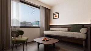 Uma sala de estar moderna com um sofá, duas poltronas, uma mesa de centro e uma janela com cortinas.