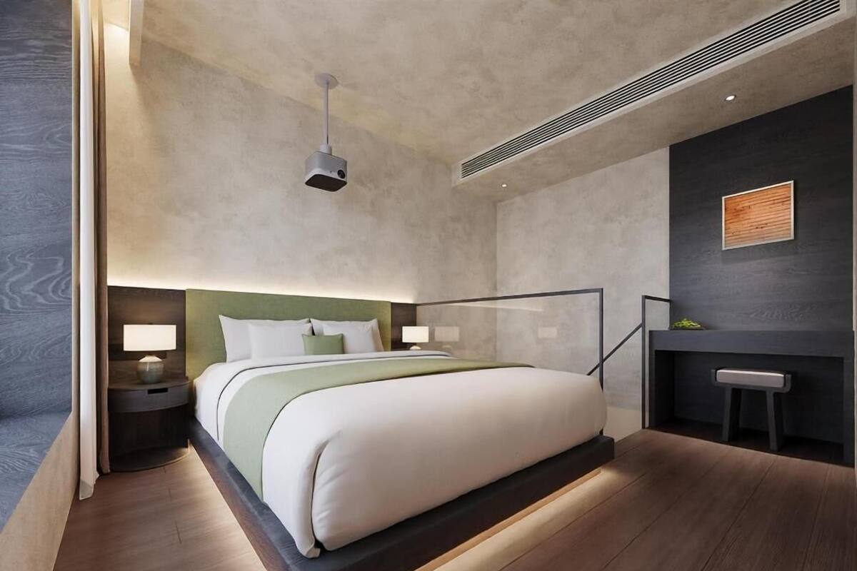 Ein modernes Hotelzimmer mit einem großen Bett, Nachttischen, einem Schreibtisch und einem Sessel.
