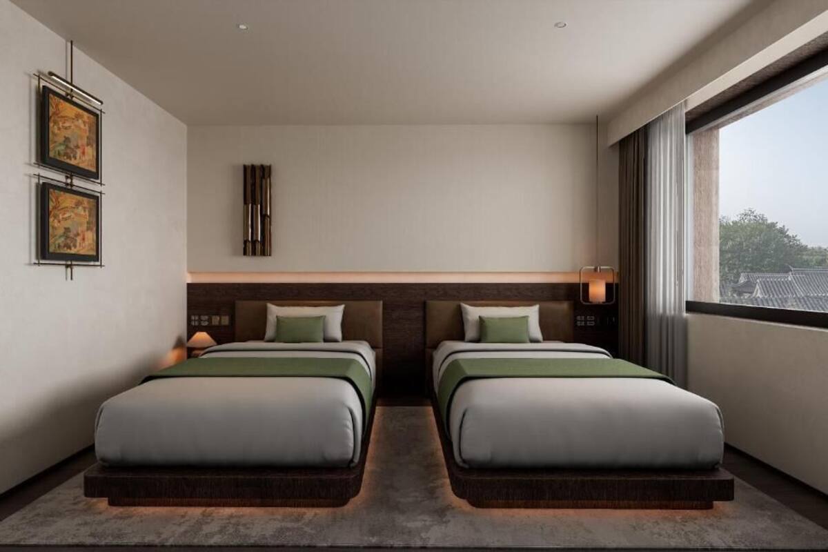 Ein modernes Hotelzimmer mit zwei Betten, einem großen Fenster und Kunstwerken an der Wand.