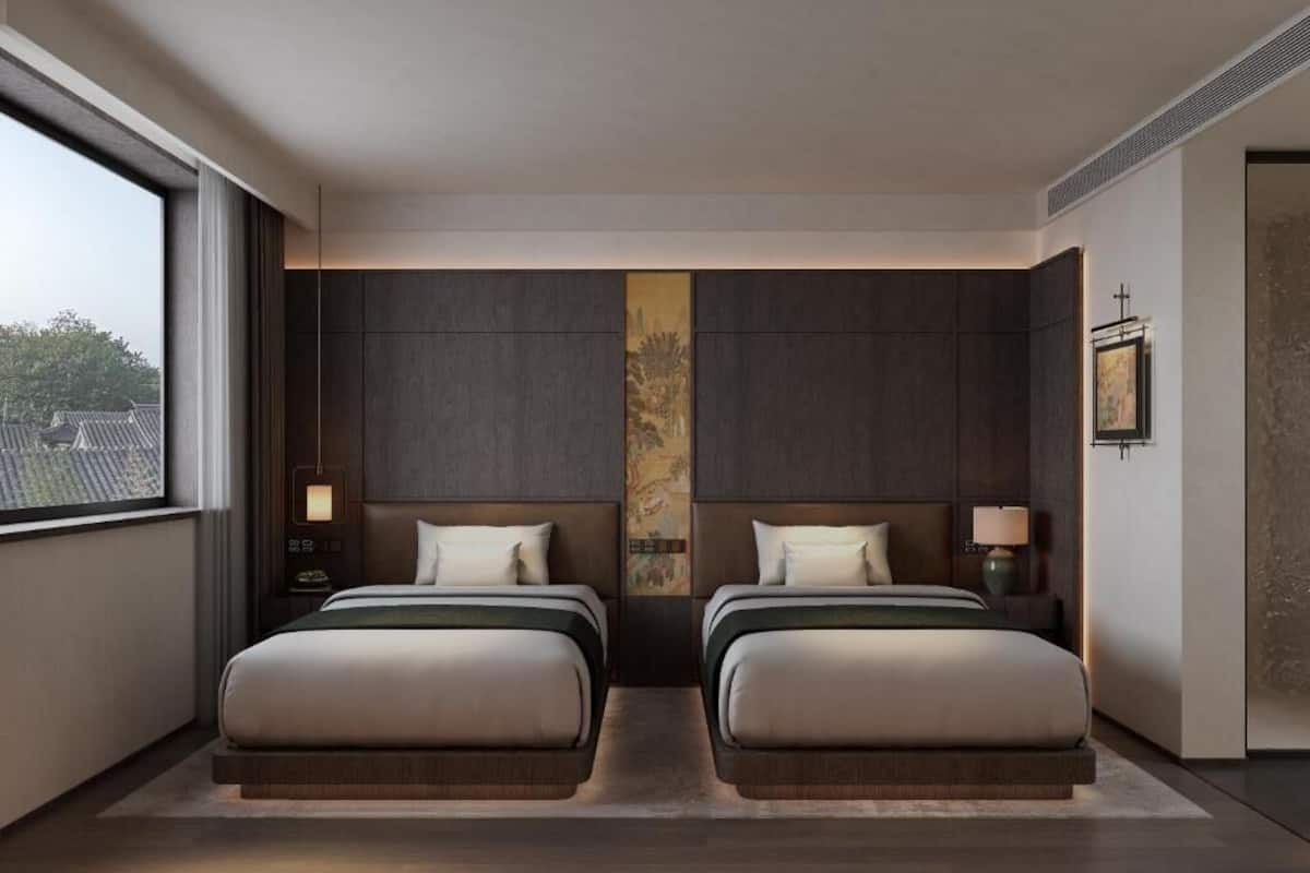 Ein modernes Hotelzimmer mit zwei Betten, einem großen Fenster und Blick auf die Stadt.