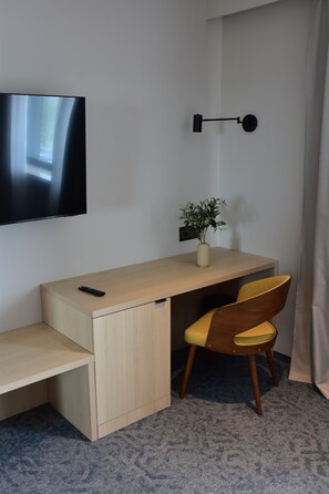 Une pièce comprenant un bureau, une chaise, un téléviseur et une plante en pot.