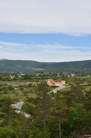 Un paisaje rural con un camino sinuoso, campos verdes y edificios dispersos.