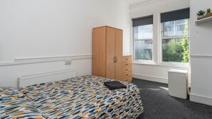 A bedroom with a bed, a wardrobe, a radiator, a window, and a small white appliance. - Room 3 - The Archers (Southampton)