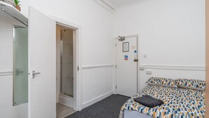 A hotel room with a bed, a shower, and a door leading to a bathroom. - Room 3 - The Archers (Southampton)