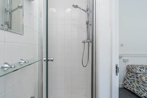 Eine begegnete Duschkabine mit Handbrause und am Wand montierter Armatur.
