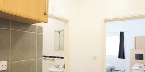 A bathroom with a shower, sink, and a view of a balcony. - Pebbles Guest House - Flat 1 (Southampton)