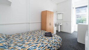 A bedroom with a bed, a wardrobe, a sink, and a window. - Room 2 - The Archers (Southampton)