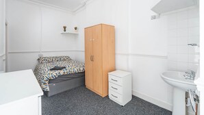 A bedroom with a bed, a wardrobe, a bedside table, and a bathroom with a sink and mirror. - Room 2 - The Archers (Southampton)
