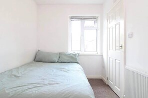 A small, single-bed room with a window and a door. - Coventry Road Studio Flat (Southampton)