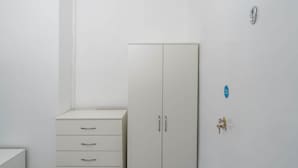 Un armario blanco con dos puertas y una cómoda pequeña con tres cajones.