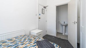 Ein Schlafzimmer mit Bett, Nachttisch und einer Tür zu einem Badezimmer.