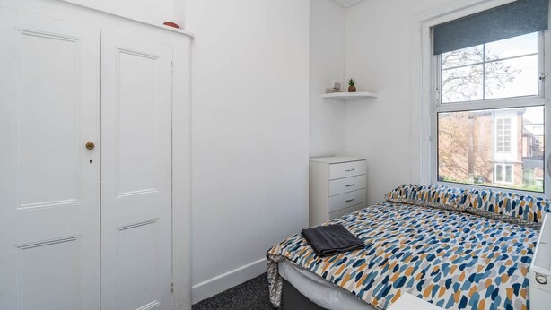 Ein Schlafzimmer mit Bett, Schrank, Nachttisch und einem Fenster mit Aussicht.