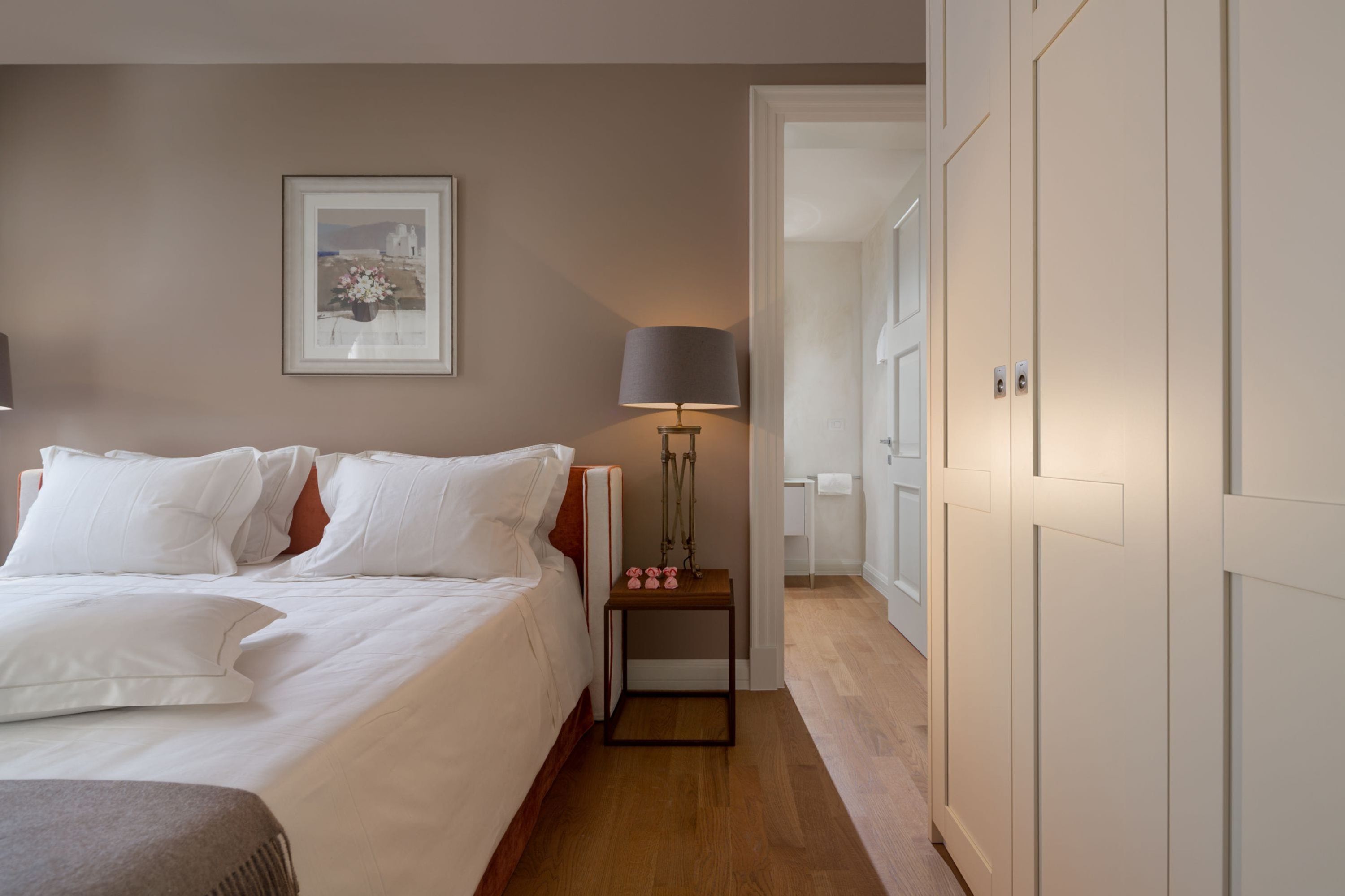 A bedroom with a bed, bedside lamp, bedside table, and a framed picture on the wall.