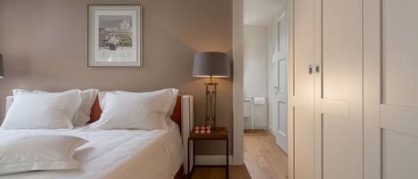 A bedroom with a bed, bedside lamp, bedside table, and a framed picture on the wall.