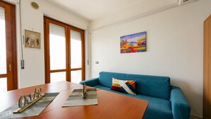 Una stanza con un tavolo di legno, un divano blu, un quadro appeso alla parete e un portafortuna decorativo al muro.