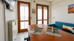 Un soggiorno con tavolo in legno, divano blu e televisione a parete.