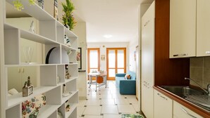Una cucina con mobili bianchi, un lavandino e un'area pranzo con tavolo e sedie.