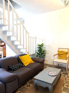 Ein Wohnzimmer mit einem braunen Sofa, einem weißen Couchtisch, einem gelben Sessel und einer Treppe.