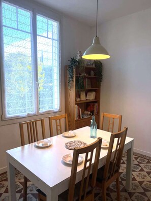 Ein Essbereich mit Tisch, Stühlen, einer Hängelampe, einem Bücherregal und einem Fenster mit Blick.