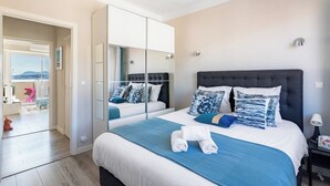Un dormitorio con cama, un espejo grande, una mesita de noche y vistas al exterior.