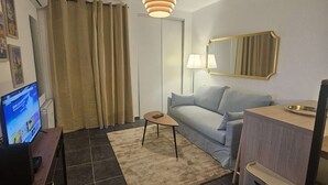 Un salon moderne avec un canapé, une table basse, un téléviseur et une lampe.