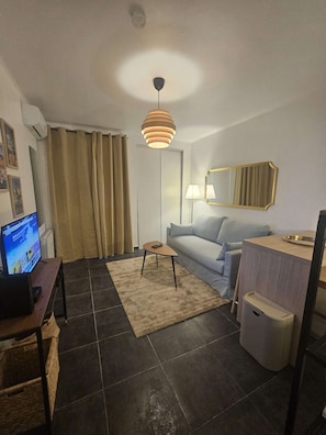 Ein modernes Wohnzimmer mit einer Couch, einem Couchtisch, einem Fernseher und einer Lampe.