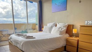 Une chambre à coucher avec un lit, des tables de chevet, une lampe et une vue sur la ville.