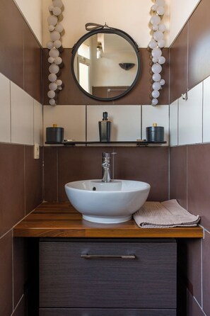 Un bagno con un lavandino bianco, uno specchio e un asciugamano sul ripiano.