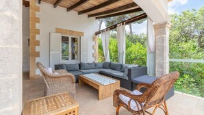 Eine Terrassengruppe im Freien mit einer Sofaecke, Korbstühlen und einem Holztisch.