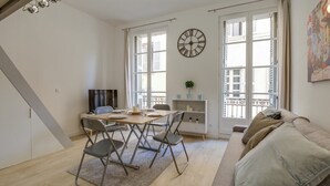 Een moderne woonkamer met een eethoek, grote ramen en een bank.