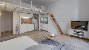 Een compacte leefruimte met een slaapverdieping, kitchenette en een televisie.