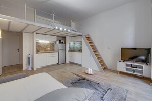 A compact living space with a loft bedroom, kitchenette, and a TV. - Grand studio mezzanine/Proche port/Clim/Wi-Fi (TOULON)