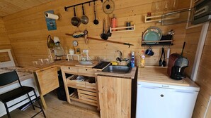 A compact kitchen with wooden walls, a sink, a coffee maker, and various utensils. - Cabin Sleeps 2 With Enclosed Garden (Tavira)