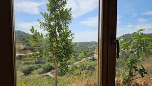 A window with a view of a rural landscape, including trees and a hilly terrain. - Cabin Sleeps 2 With Enclosed Garden (Tavira)