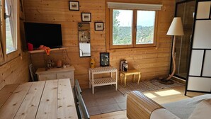 A wooden cabin interior with a TV, a small table, a sofa, and a window with a view. - Cabin Sleeps 2 With Enclosed Garden (Tavira)