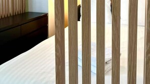 Et hotelværelse med en seng, et natbord og en træafskærmning.