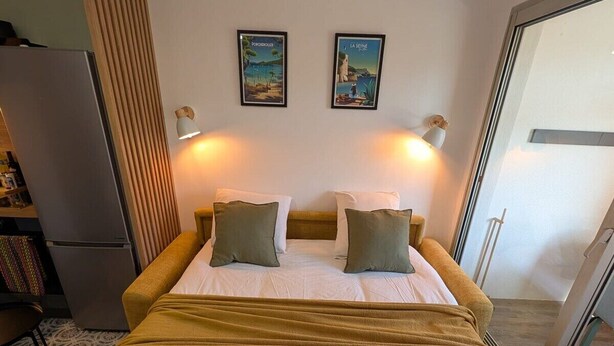 A bed with a headboard, two wall-mounted lamps, and two framed pictures. - Joli studio • 5 min plages • Tout à pied (Saint-Mandrier-sur-Mer)
