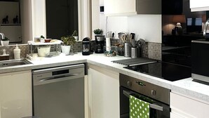 A modern kitchen with a dishwasher, oven, and a built-in stove. - Joli T3 spacieux & climatisé – confort + wifi (Toulon)