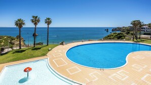 Ein Pool mit Blick auf den Ozean, Palmen und einem klaren Himmel.