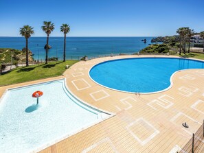 Ein Pool mit Blick auf den Ozean, Palmen und einem klaren Himmel.